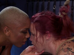 Ebony domme in leather top turns the redhead into her slave