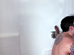 Muscular tattooed guy jerks off and fucks a sex toy in the shower